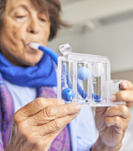 spirometer for breathing exercises. senior woman in hospital room practicing with spirometer