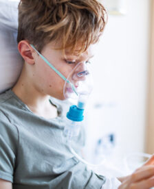 School age boy inhaling with nebuliser